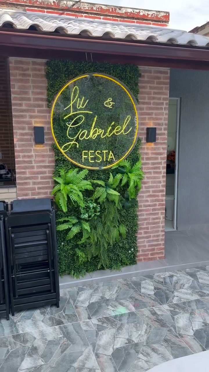 Painel neon com o nome Lu & Gabriel Festa em parede de plantas